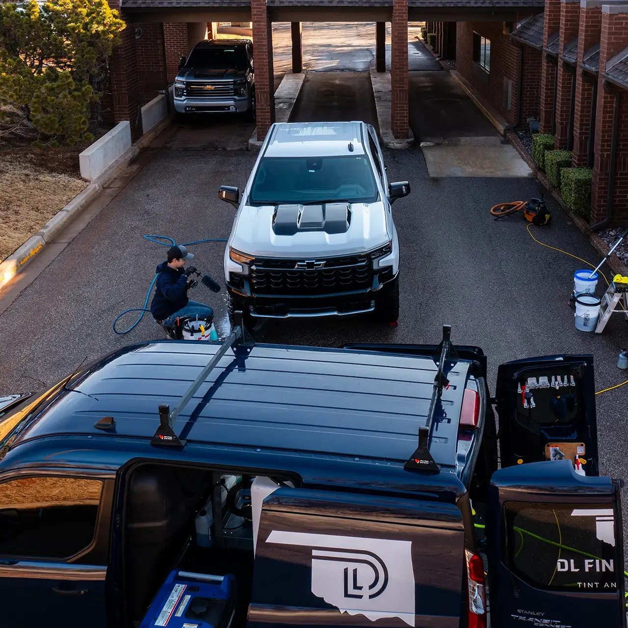 Dante washing vehicle behind DL Fine Auto van