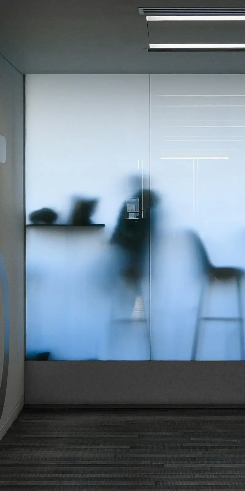 frosted-glass A frosted office window with the silhouette of a person sitting at a table behind it